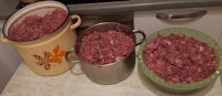 three pots with meat in them on a kitchen counter